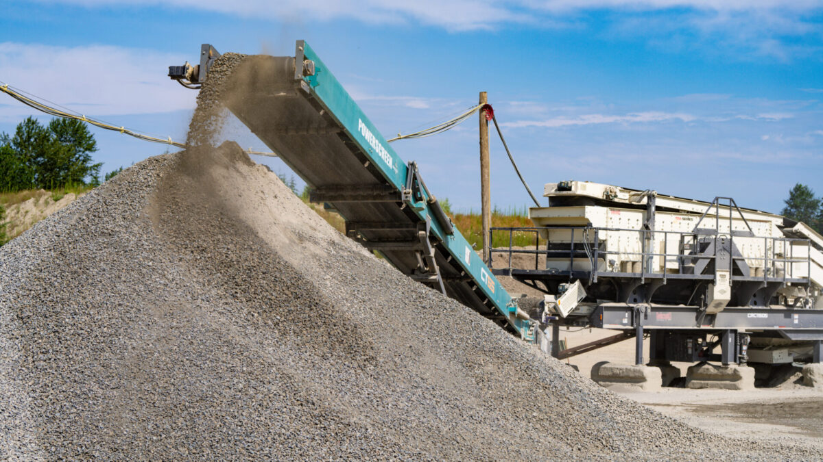 Powerscreen CT65 conveyor stockpiling crushed gravel beside a Cedarapids CRC1150S portable cone and screen plant in a quarry, producing clean, high-quality aggregate for construction applications.