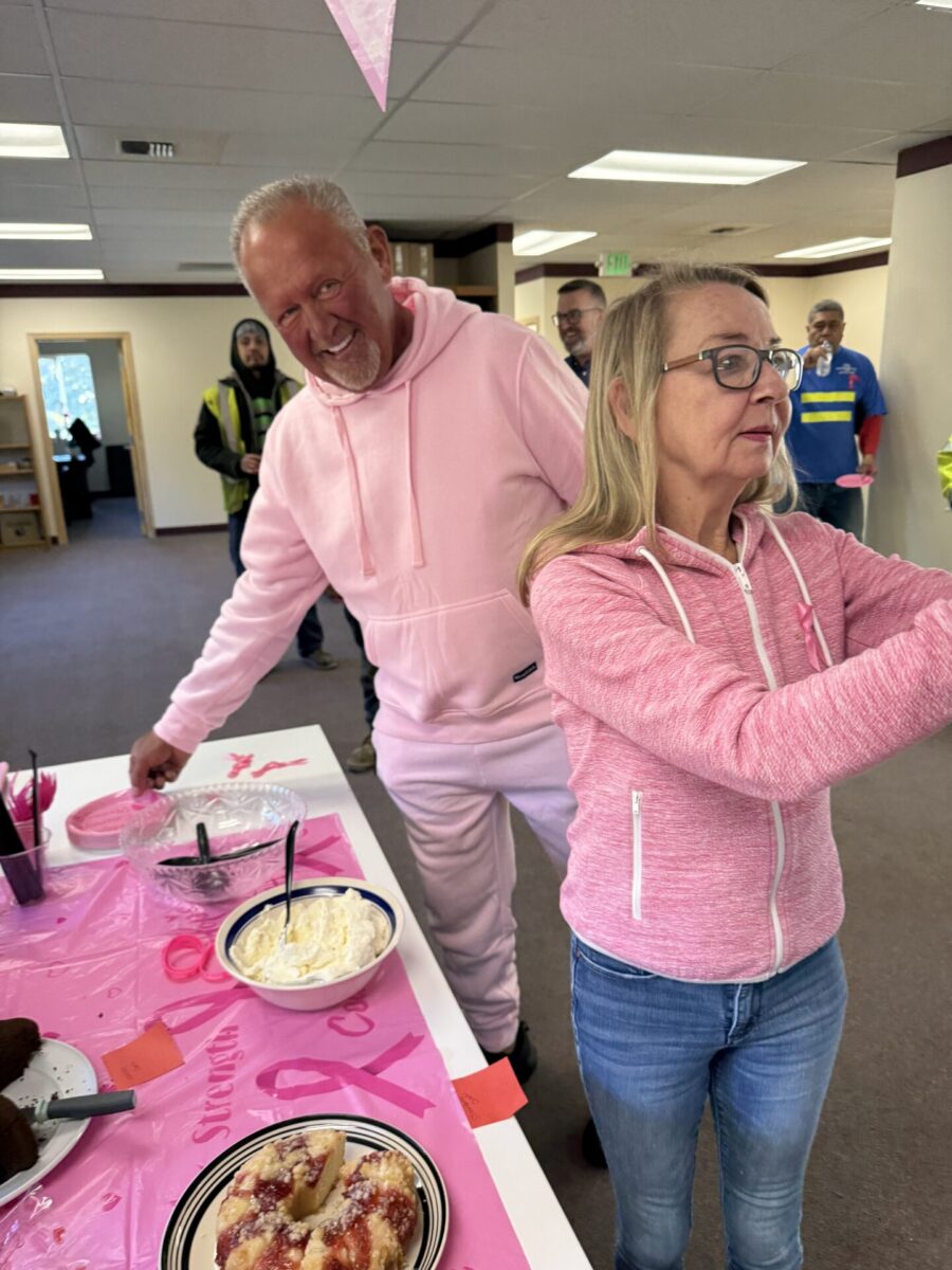 Man and woman wearing pink for a breast cancer awareness bake sale