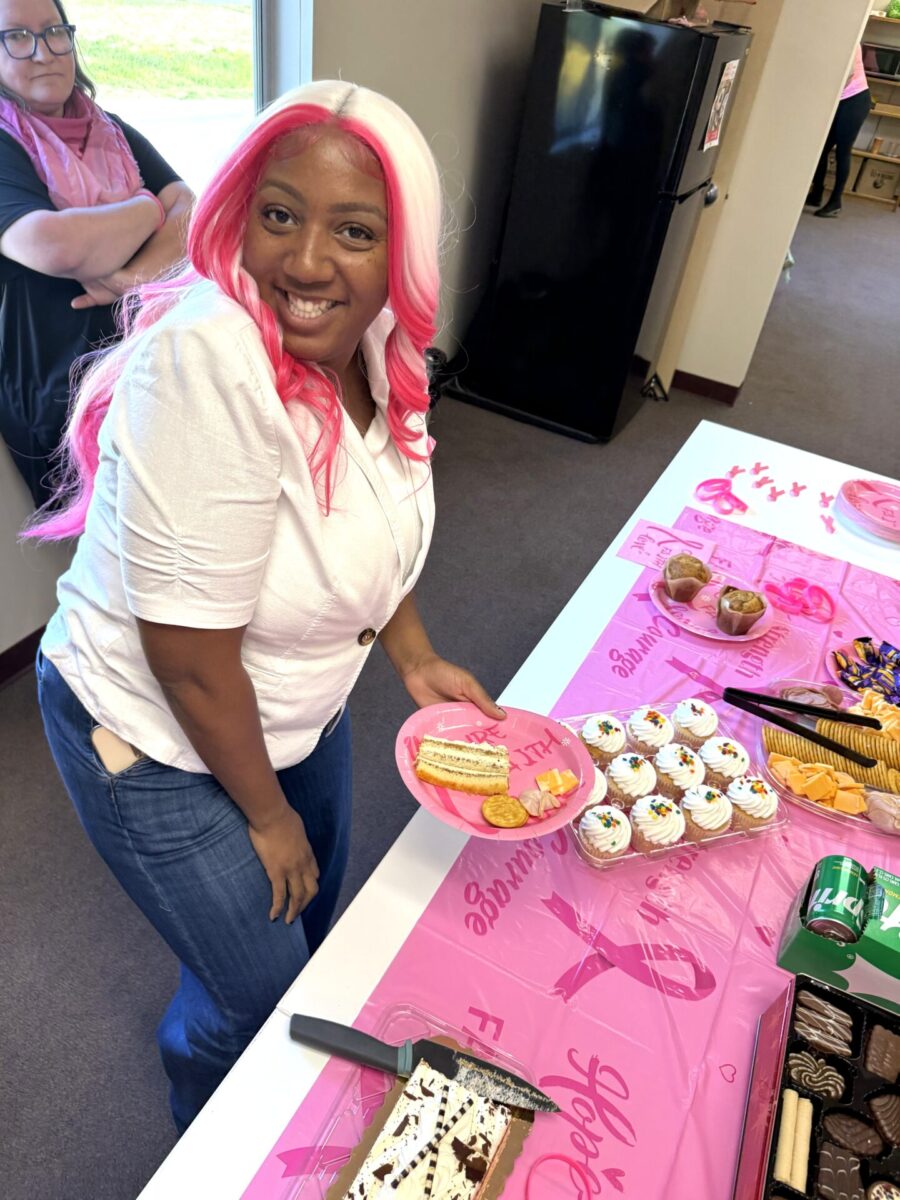 Woman smiling and getting pastries at a breast cancer awareness bake sale